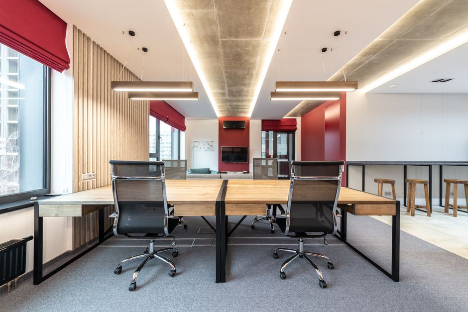 Interior of modern workplace with wooden table and chairs near window with jalousie under lamps